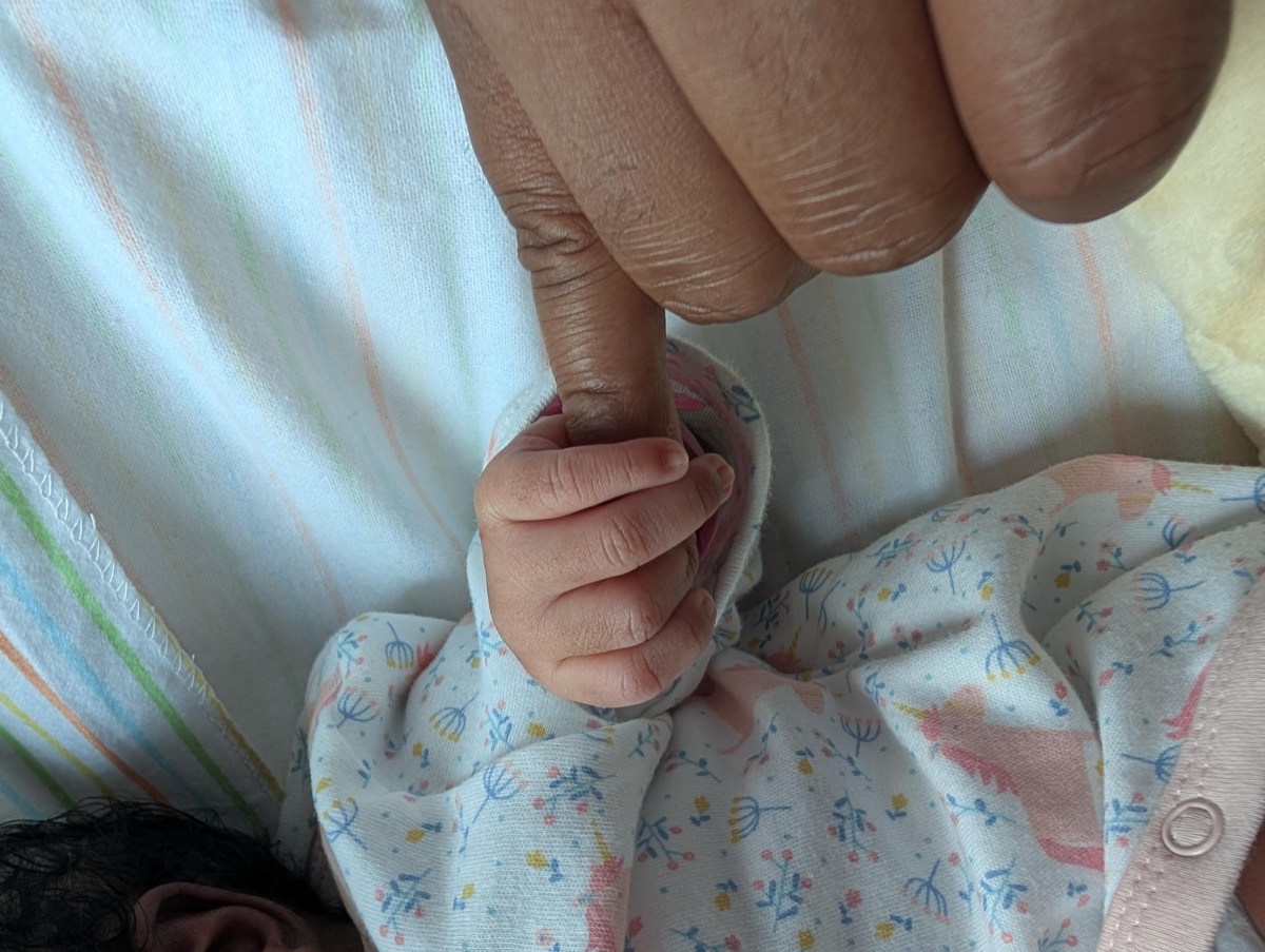 A baby’s hand holding Sammy’s finger